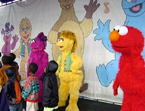 South African children gather with walk-around versions of Takalani Sesame characters in a rally for Kami.